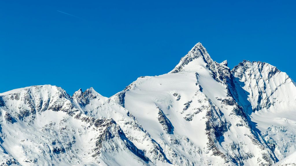Stunning view of snow-covered mountains in Korutany, Austria, under a clear blue sky.
